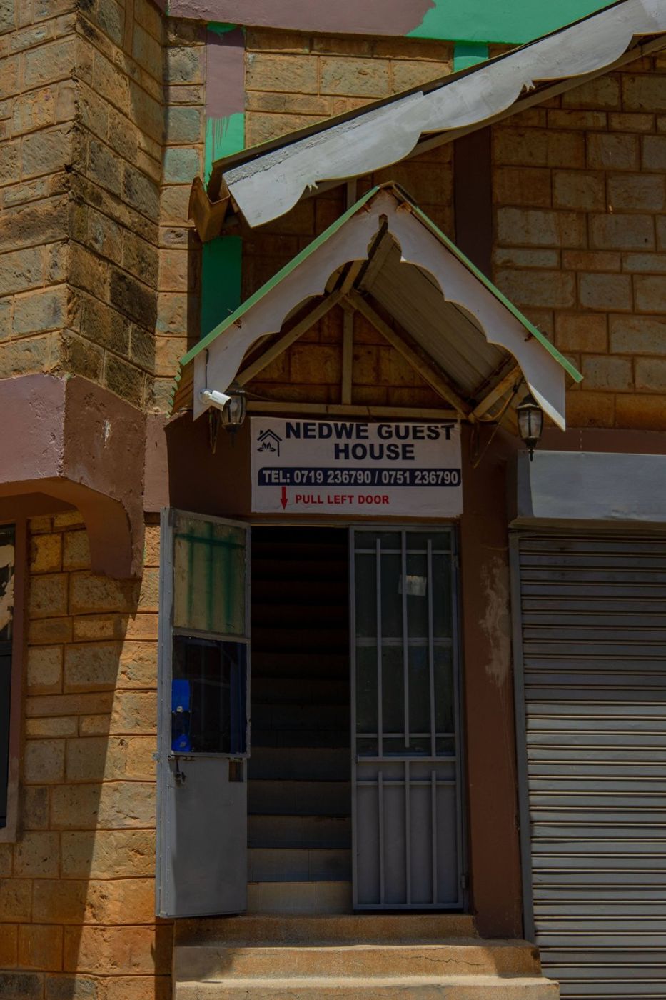 The NEDWE Guest House entrance with its sign and phone numbers