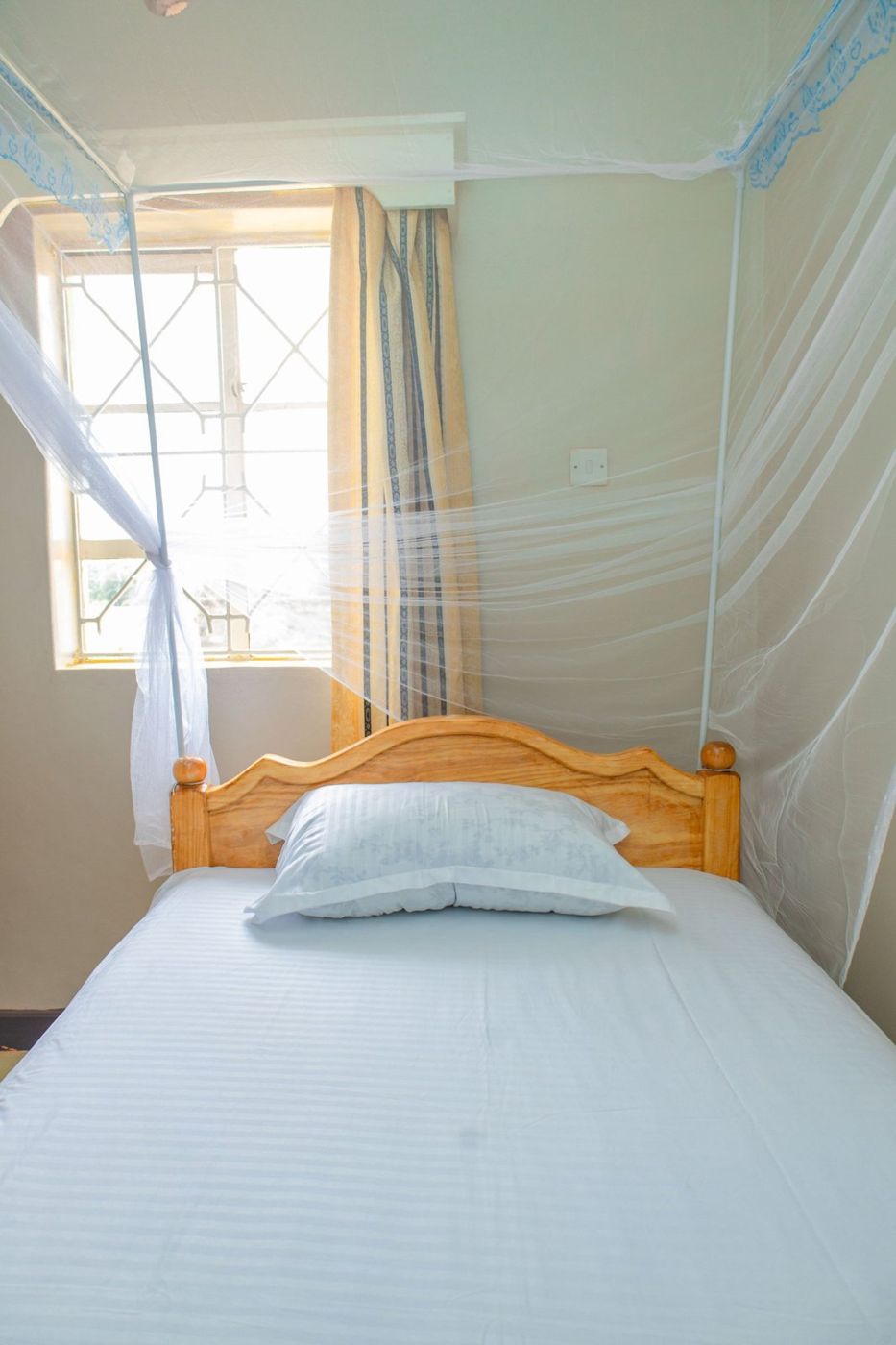 Single room with white bedding by a bright window
